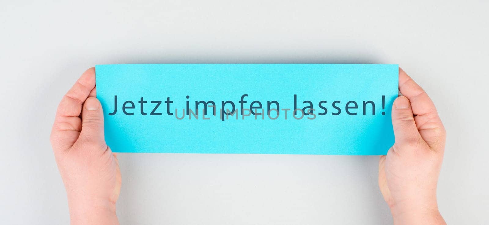 Get vaccinated now is standing in german language on the paper, Covid-19 vaccination, hands holding the message