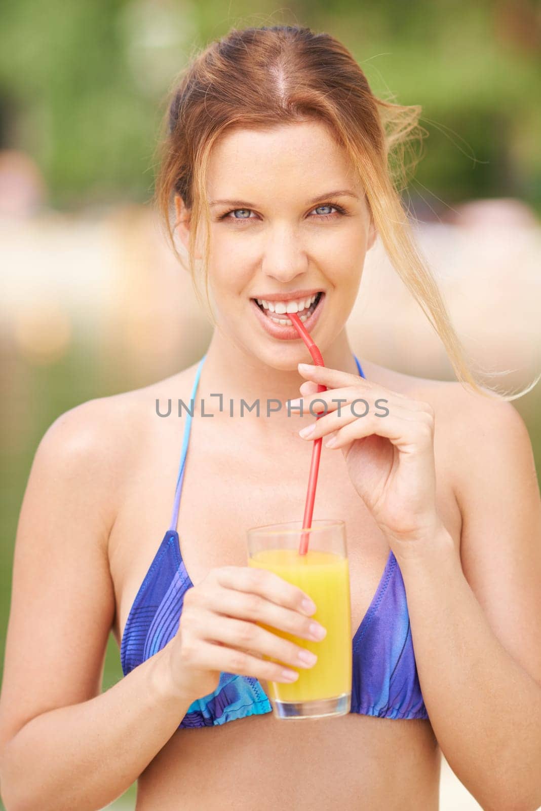 Cute girl in bikini drinking orange juice from glass