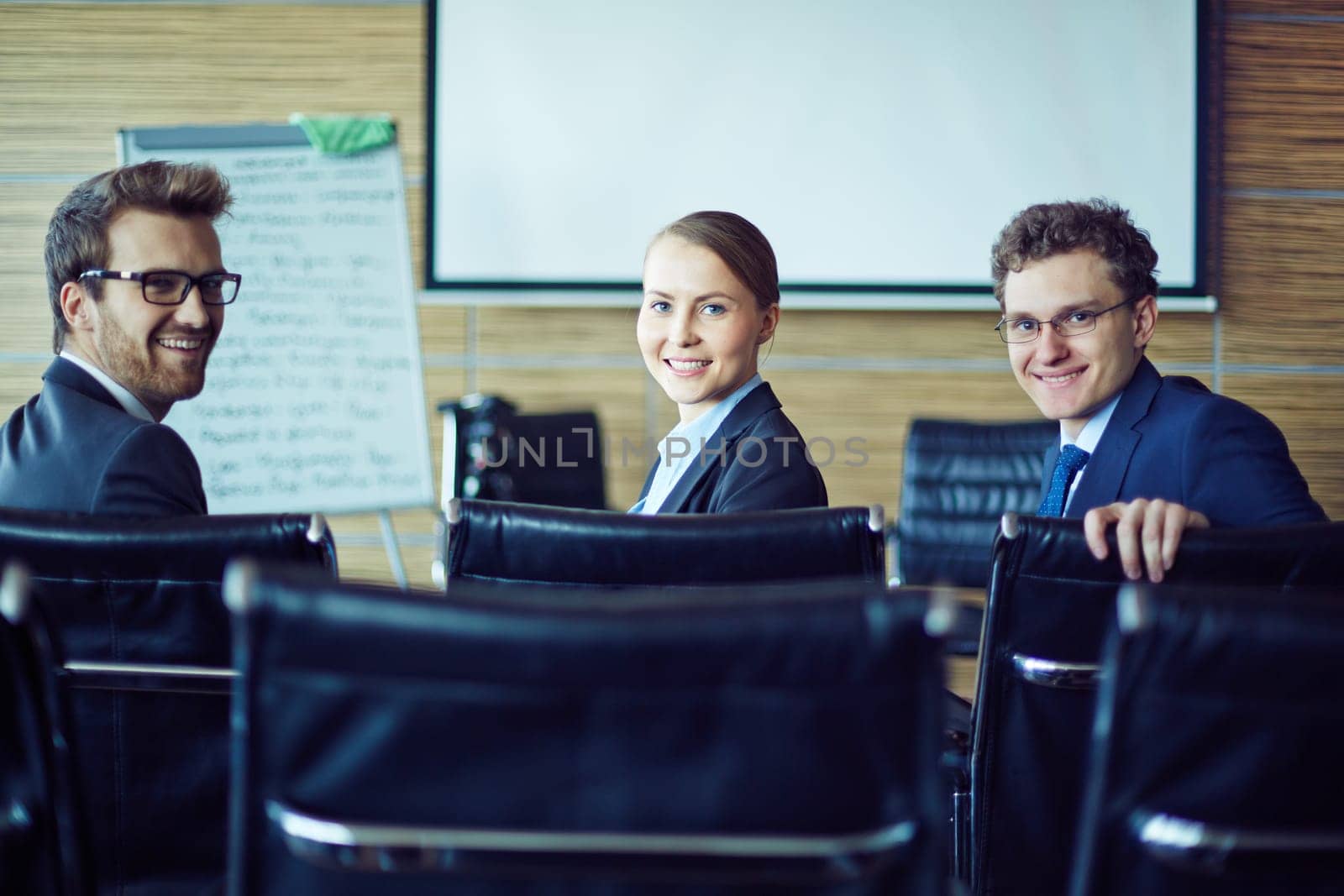 Happy co-workers looking at camera in conference hall