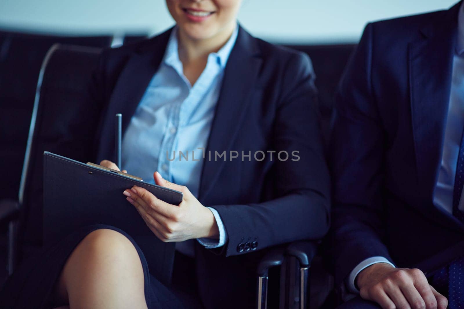 Elegant young businesswoman with clipboard making notes