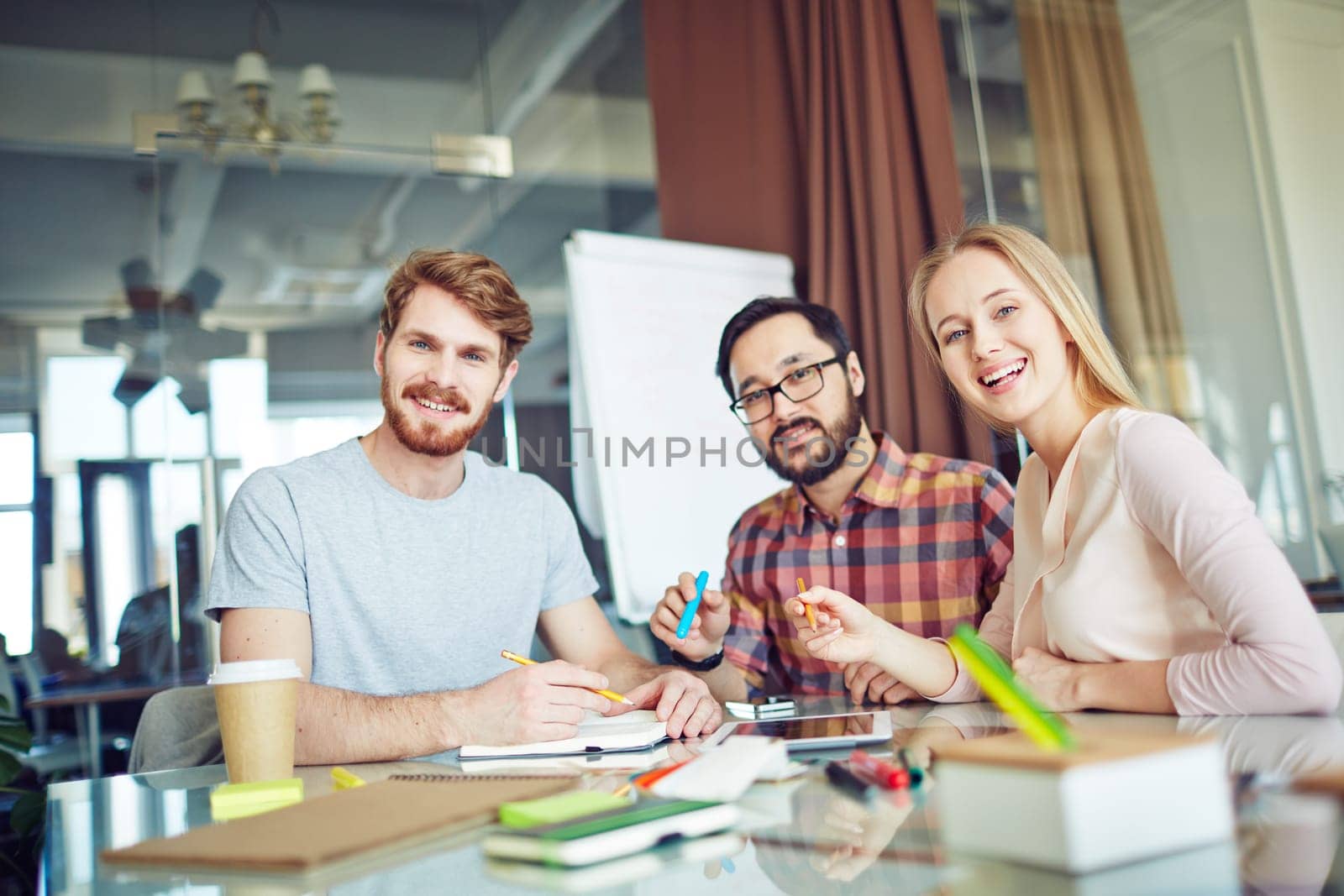Group of three cheerful business partners looking at camera