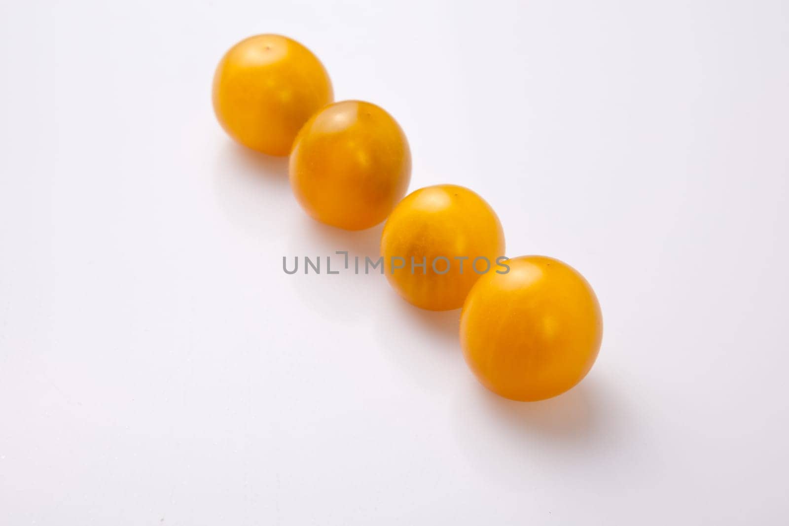 Yellow shiny cherry tomatoes. Isolated over white background