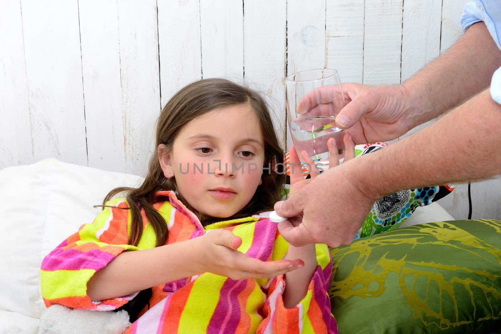 a little girl in bed taking tablet with water