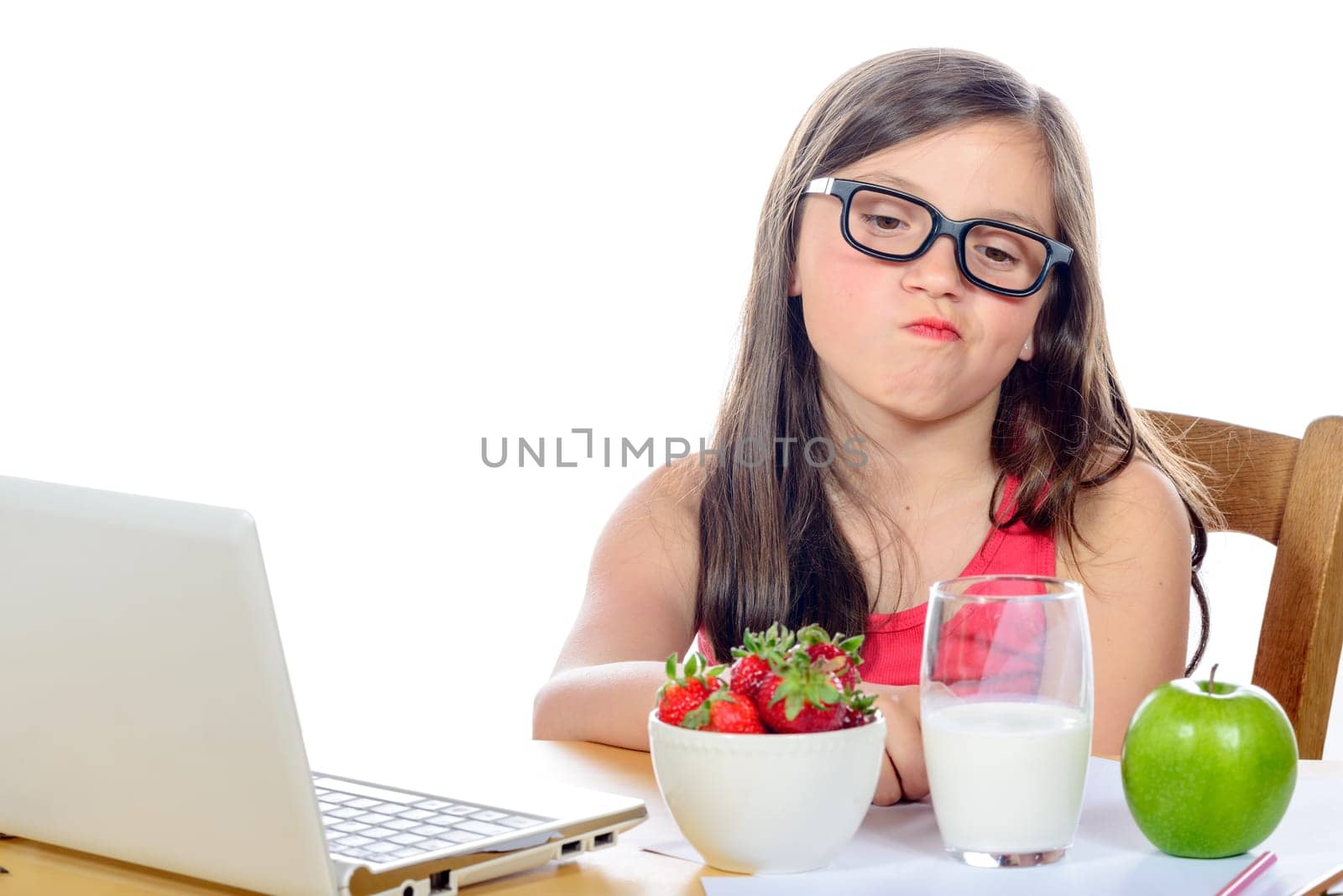 a little girl at her desk looking at his snack on white