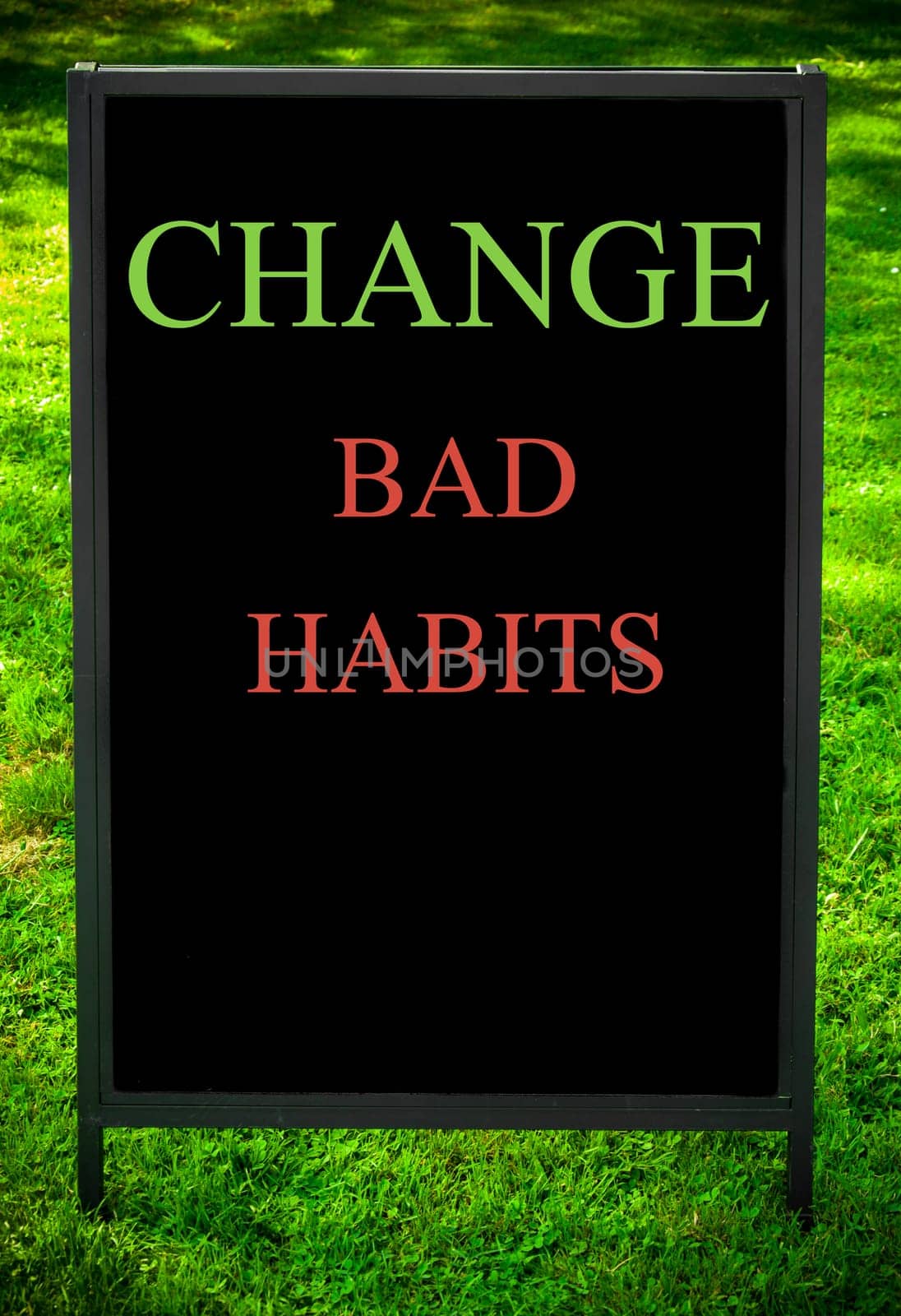 CHANGE BAD HABITS  message on sidewalk blackboard sign against green grass background. Copy Space available. Concept image