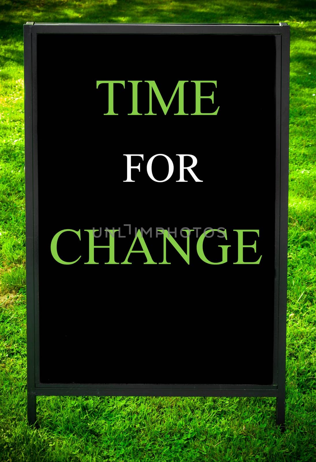 TIME FOR CHANGE  message on sidewalk blackboard sign against green grass background. Copy Space available. Concept image