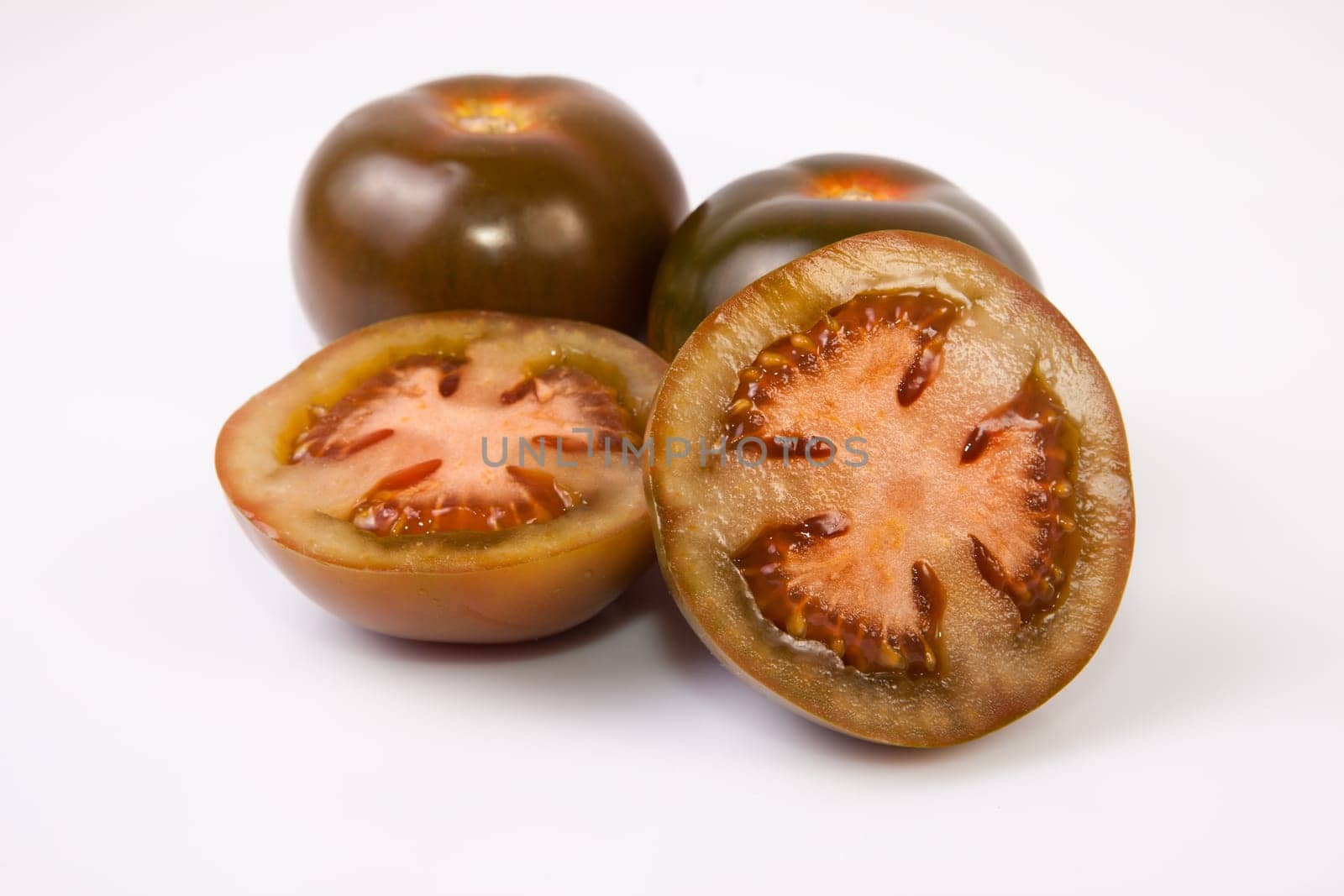 Dark green kumato tomatoes, whole and sliced. Isolated over white background