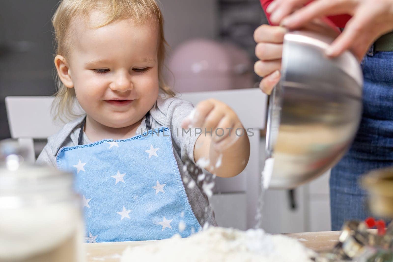 Little helper. Cute boy is  playing with sprinkling flour in the kitchen.