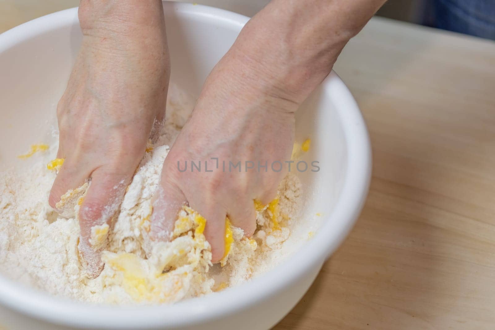 Female hands are processing dough for baking closeup in the kitchen. Horizontally.