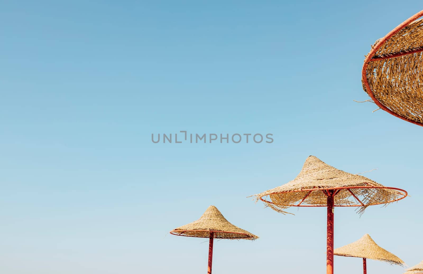 Looking up at wooden straw umbrella or thatched hut from below against beautiful cloudy blue sky view on tropical Egypt beach. Summer or winter holiday concept. Egyptian resort. High quality photo