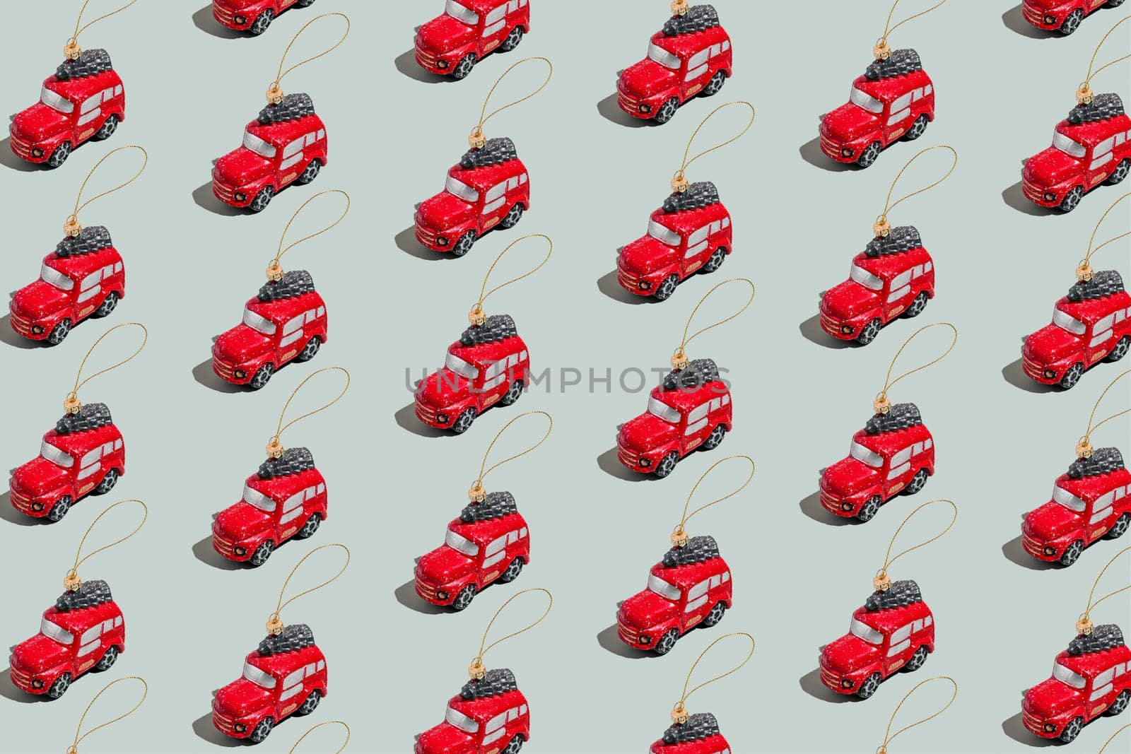 Gray green background pattern with Christmas or New Year symbol attribute objects and symbolic items concept. Small red English taxi car toy with ribbon, golden little toy fir tree. High quality photo