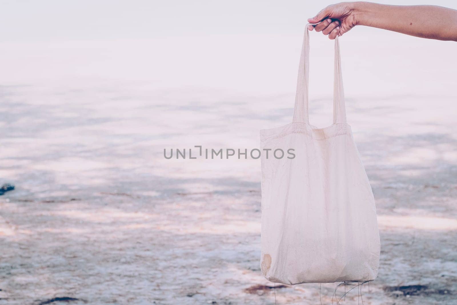 White blank cotton eco tote. Design mockup. Holding blank canvas tote bag, design mockup. Handmade shopping tote bag for girls. Beach background. Summer idea