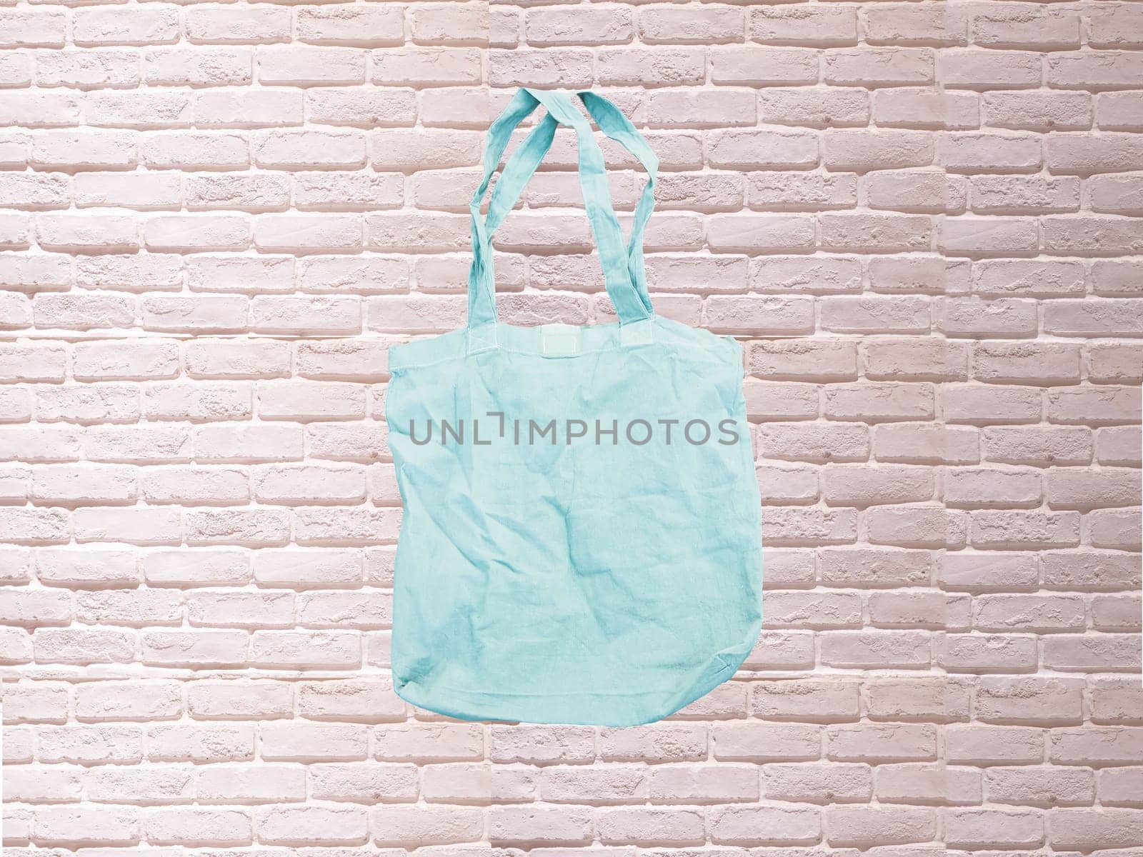 Mock up Tote bag eco hipster white cotton fabric Shopping bag in blue . white brick eall rustic background