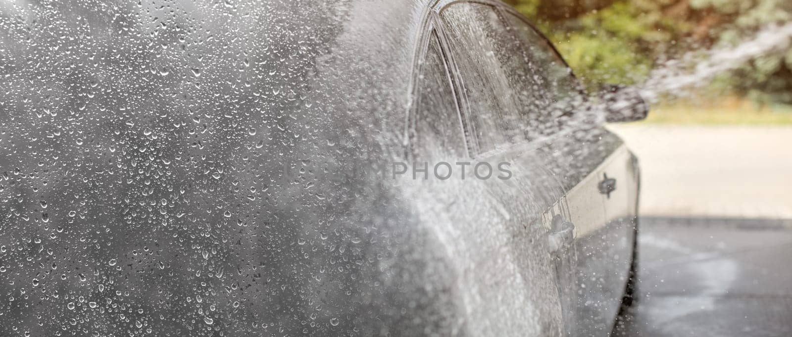 Carwash background, drops of water on the left (place for text) gradient to photo of water and shampoo spray, silver car side.
