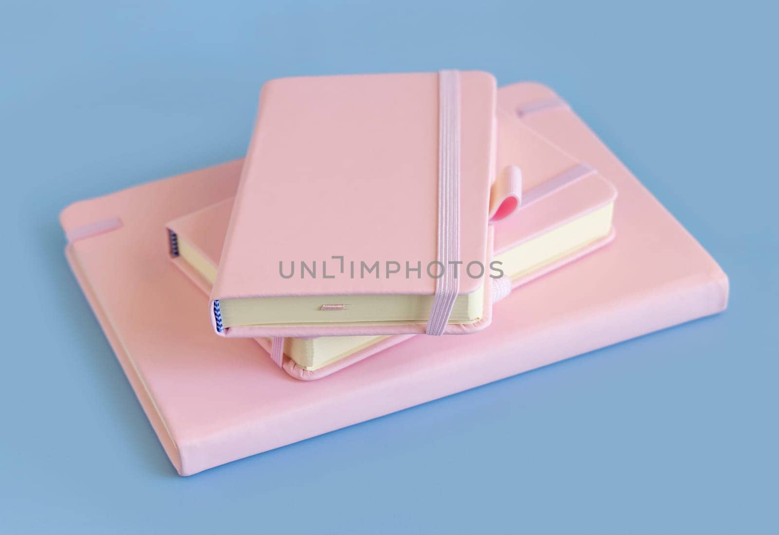 Stack of pink notebooks on light blue closeup. Textbook mockup. Educational, business and organizing concept