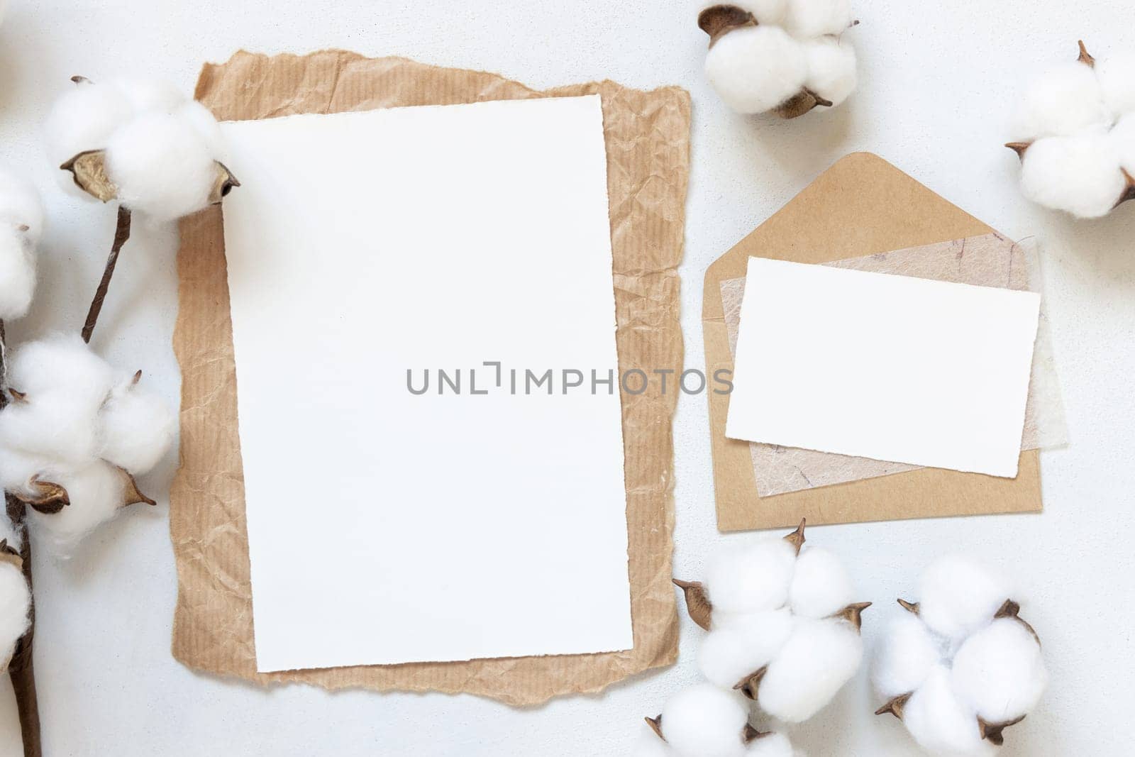 Feminine Wedding cards mockup on white table with cotton flowers top view. Elegant modern template with horizontal blank paper card, flat lay with place for text. Minimalistic stationery scene. Natural, eco-friendly concept