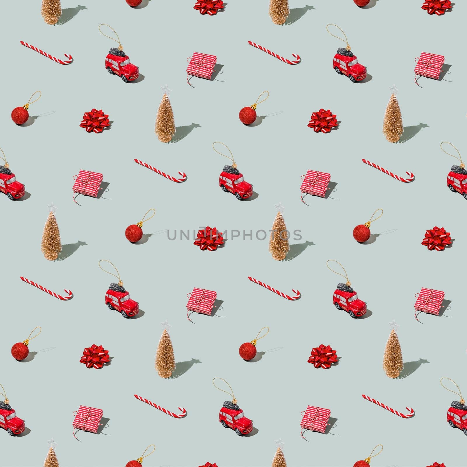 Gray green background pattern with Christmas, New Year symbol attribute objects and symbolic items concept. Small red taxi car toy, pink gift box present, lolli pop candy, lollypop, ball, fir tree