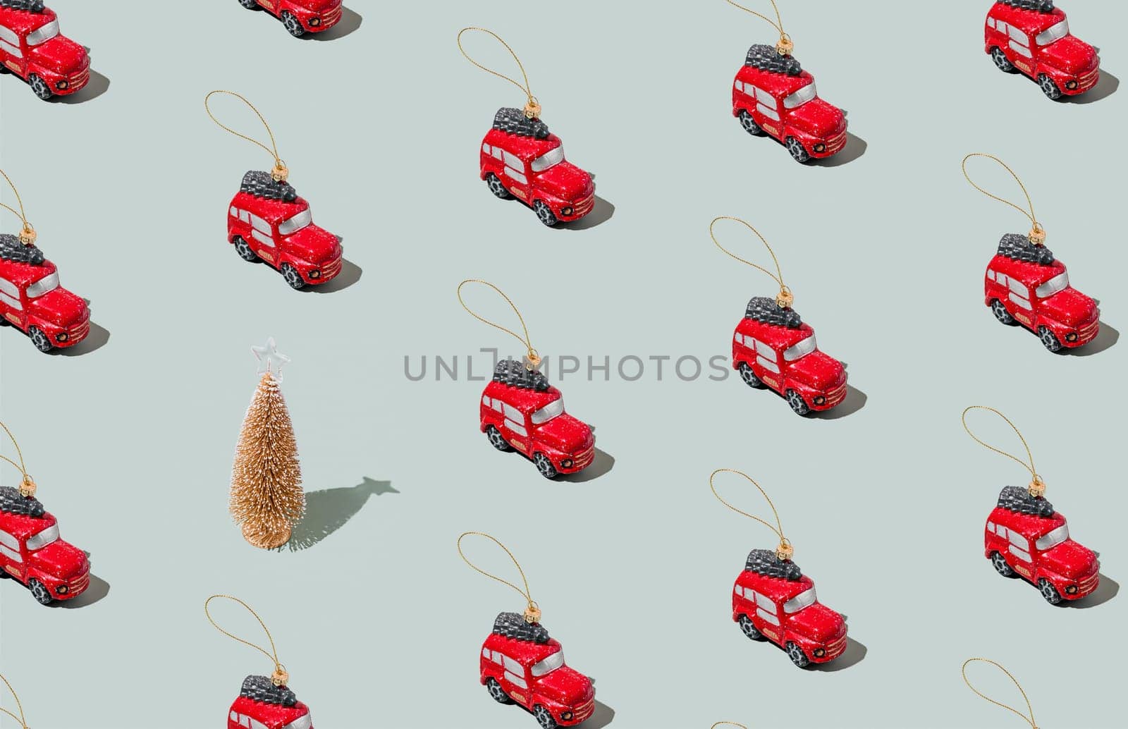 Gray green background pattern with Christmas or New Year symbol attribute objects and symbolic items concept. Small red English taxi car toy with ribbon, golden little toy fir tree. High quality photo