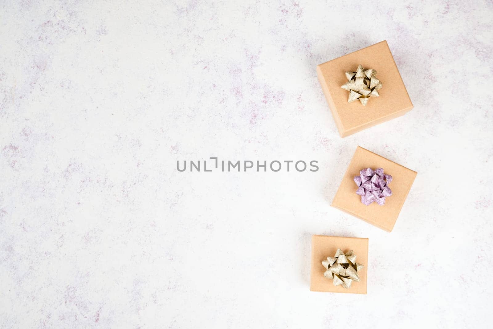 Little gift boxes on a textured light colored background, empty copy space for text, christmas season
