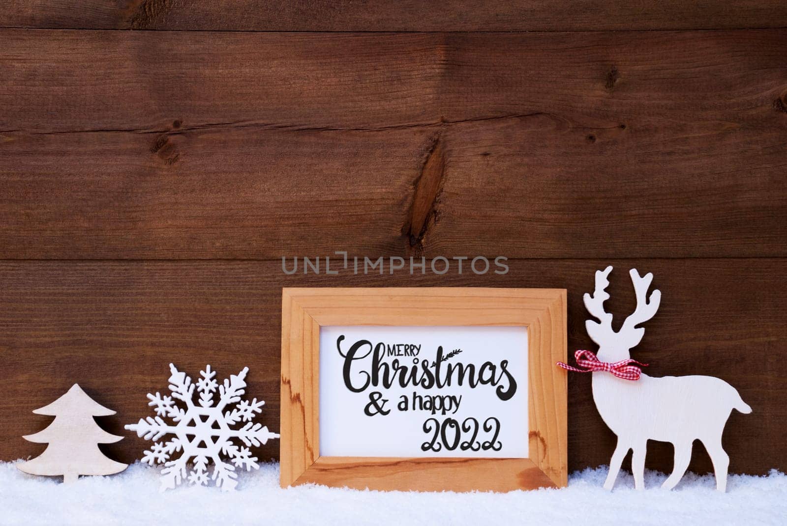 Egnlish Calligraphy Merry Christmas And Happy 2022. White Christmas Ornament Like Snowflake, Tree And Wooden Deer. Wooden Background With Snow