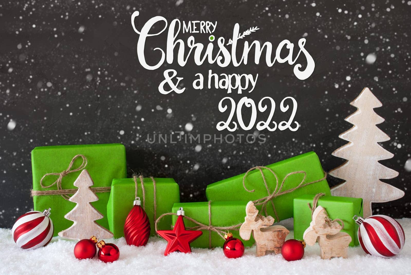 English Calligraphy Merry Christmas And A Happy 2022. Green Christmas Present With Decoration Like Tree And Ball. Black Background With Snowflakes