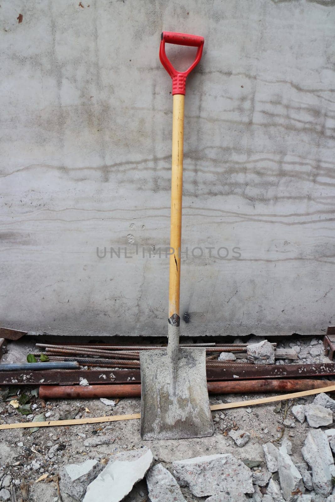 shovel leaned against the wall at a construction site