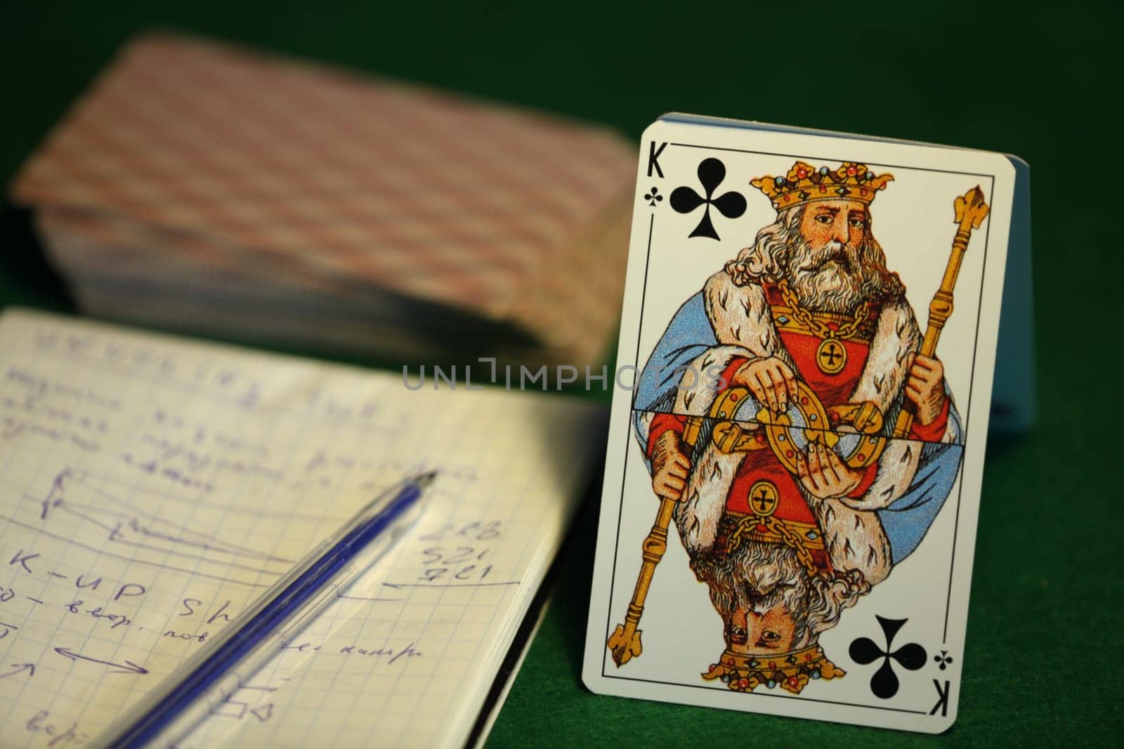 king of cross, deck of cards, paper with notes on a green cloth, card game for money, still life