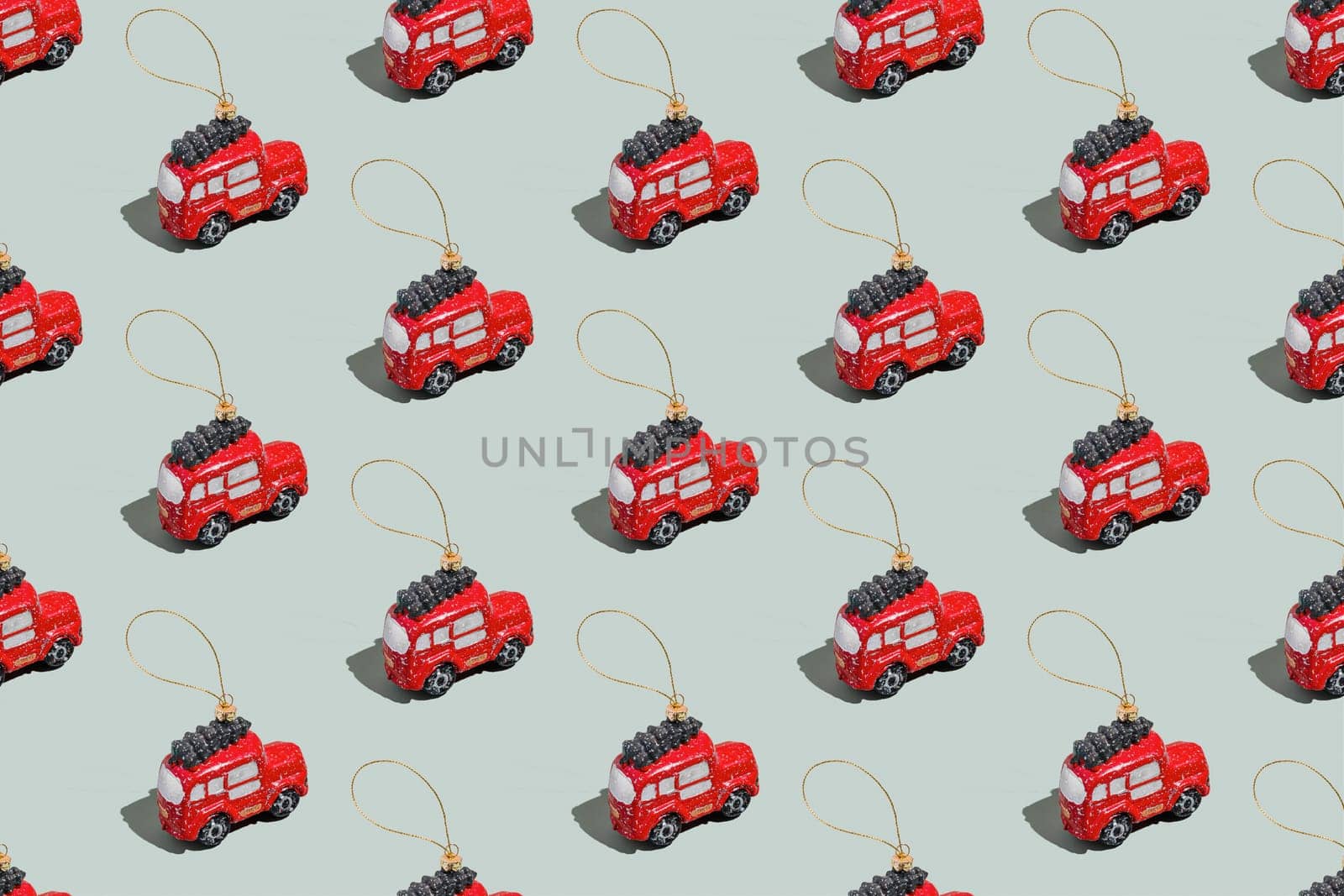 Gray green background pattern with Christmas or New Year symbol attribute objects and symbolic items concept. Small red English taxi car toy with ribbon, golden little toy fir tree. High quality photo