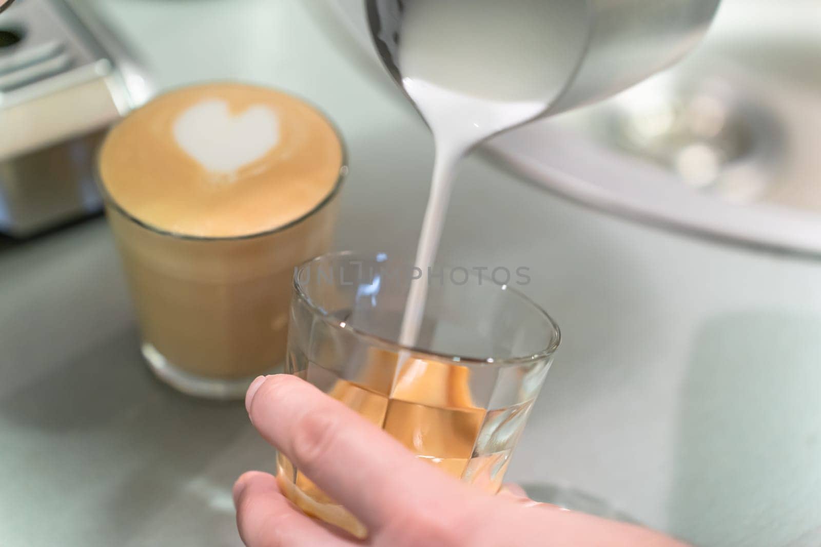 Barista pours whipped milk into a glass.