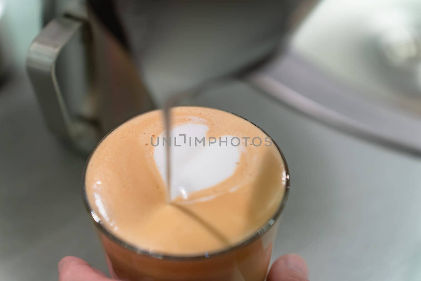 Barista made a drawing with milk in the shape of a heart in a glass with cappuccino.