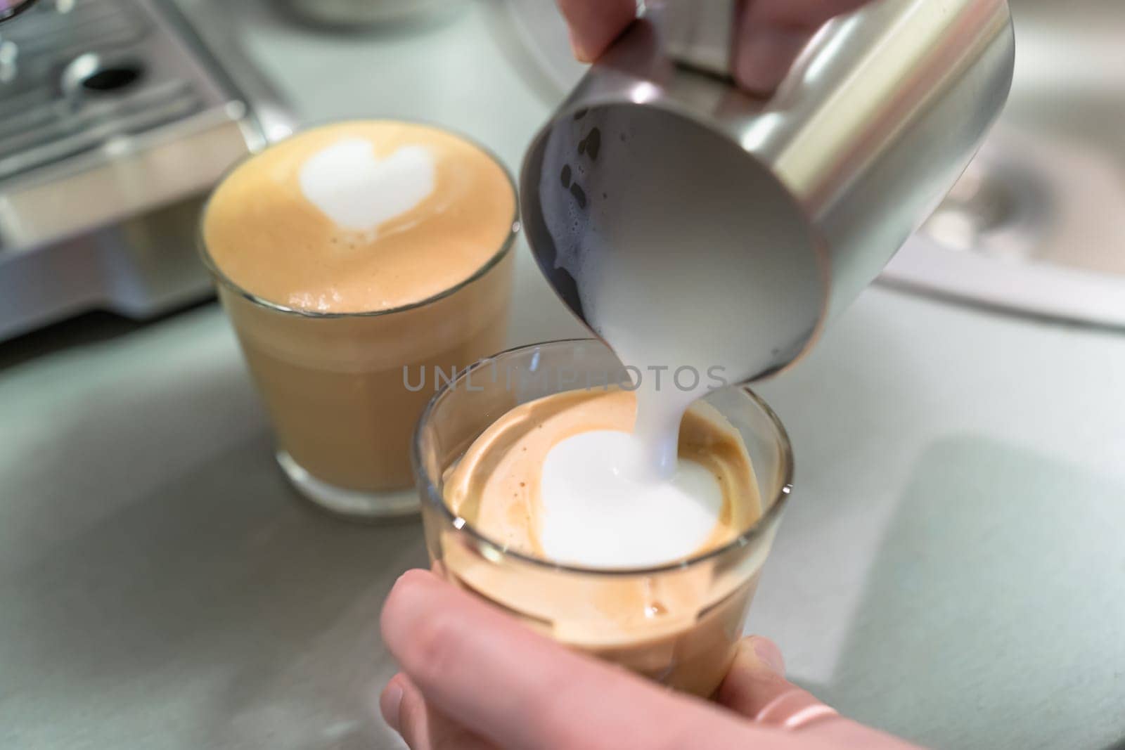 A man cooks cappuccino at home, pours milk from the pitcher into a glass.