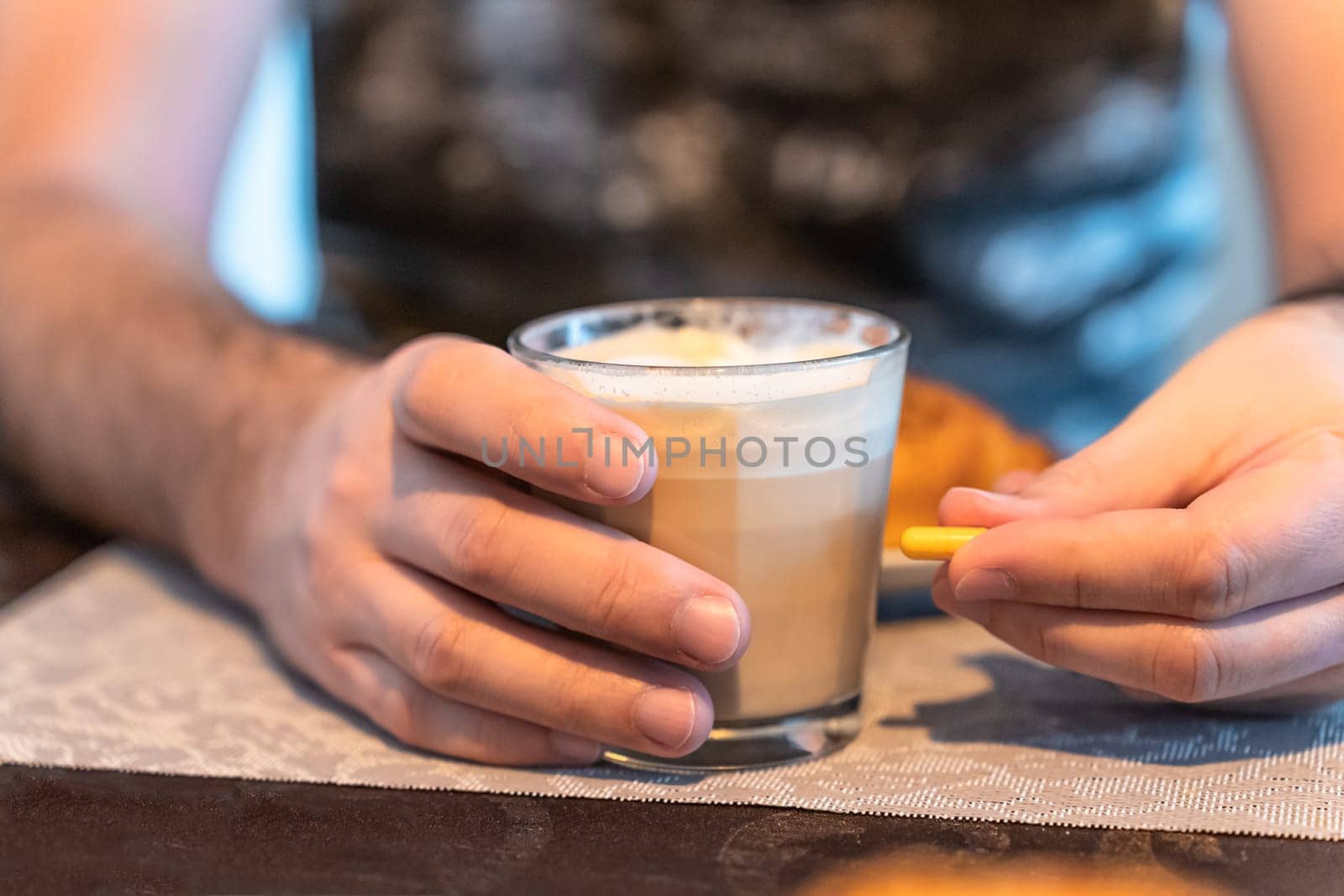 Selective focus on a man's hands, a glass of coffee in one hand and a capsule of medication in the other