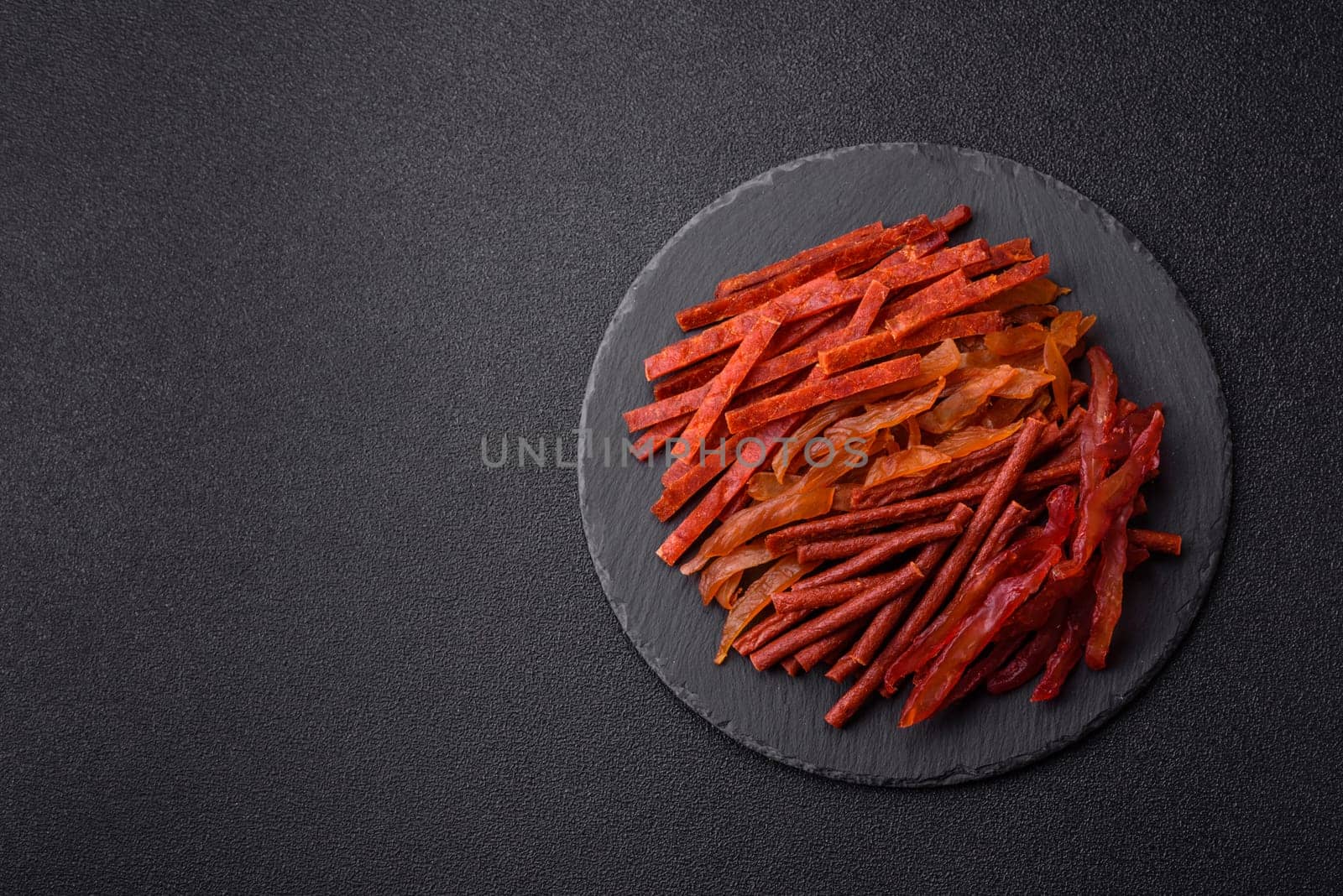 Jerky, dried fish in the form of sticks with salt, spices and herbs on a dark concrete background