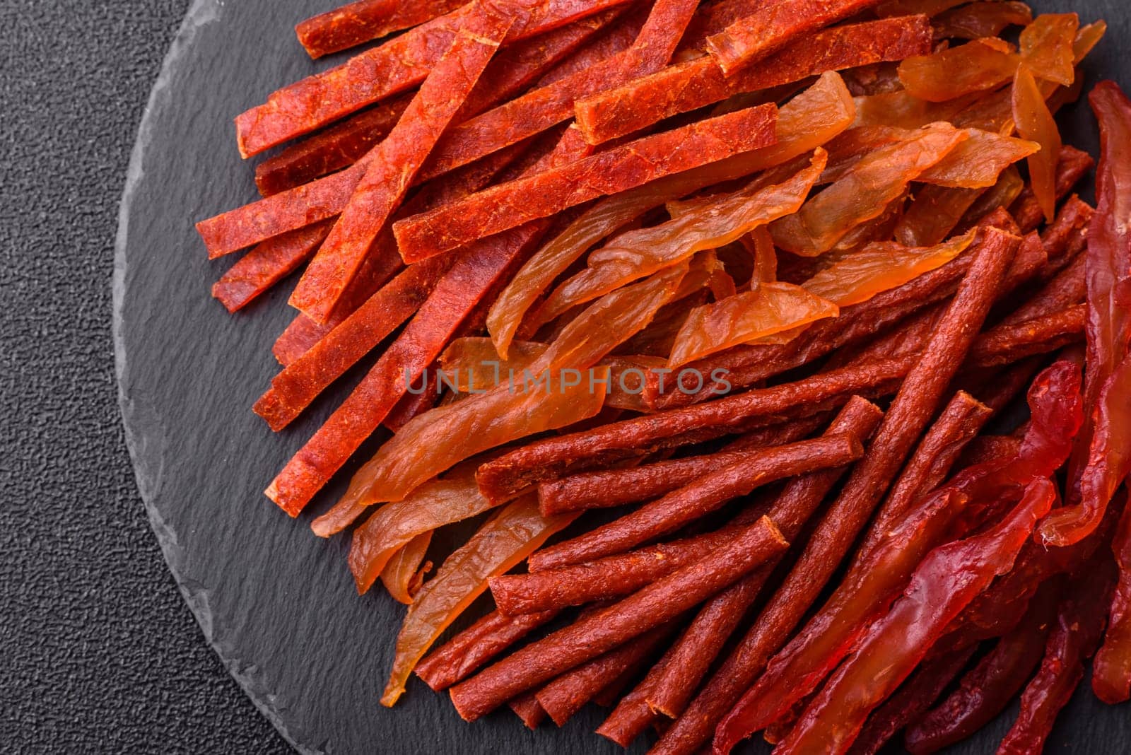 Jerky, dried fish in the form of sticks with salt, spices and herbs on a dark concrete background