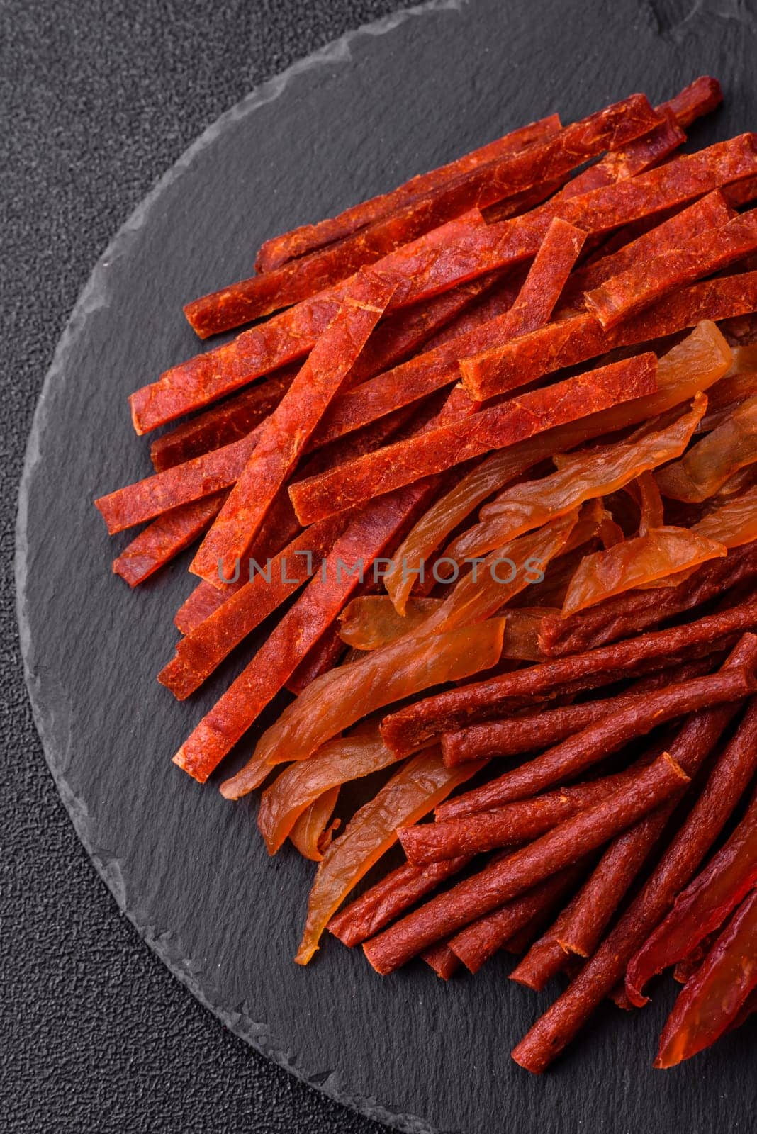 Jerky, dried fish in the form of sticks with salt, spices and herbs on a dark concrete background