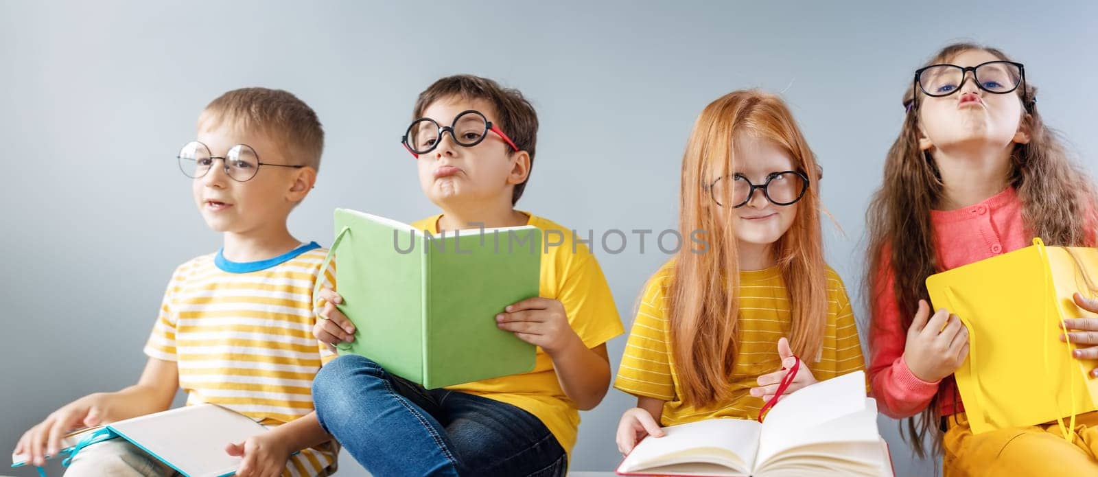 Group of children sitting indoors and reading books.. Concept of education and friendship.