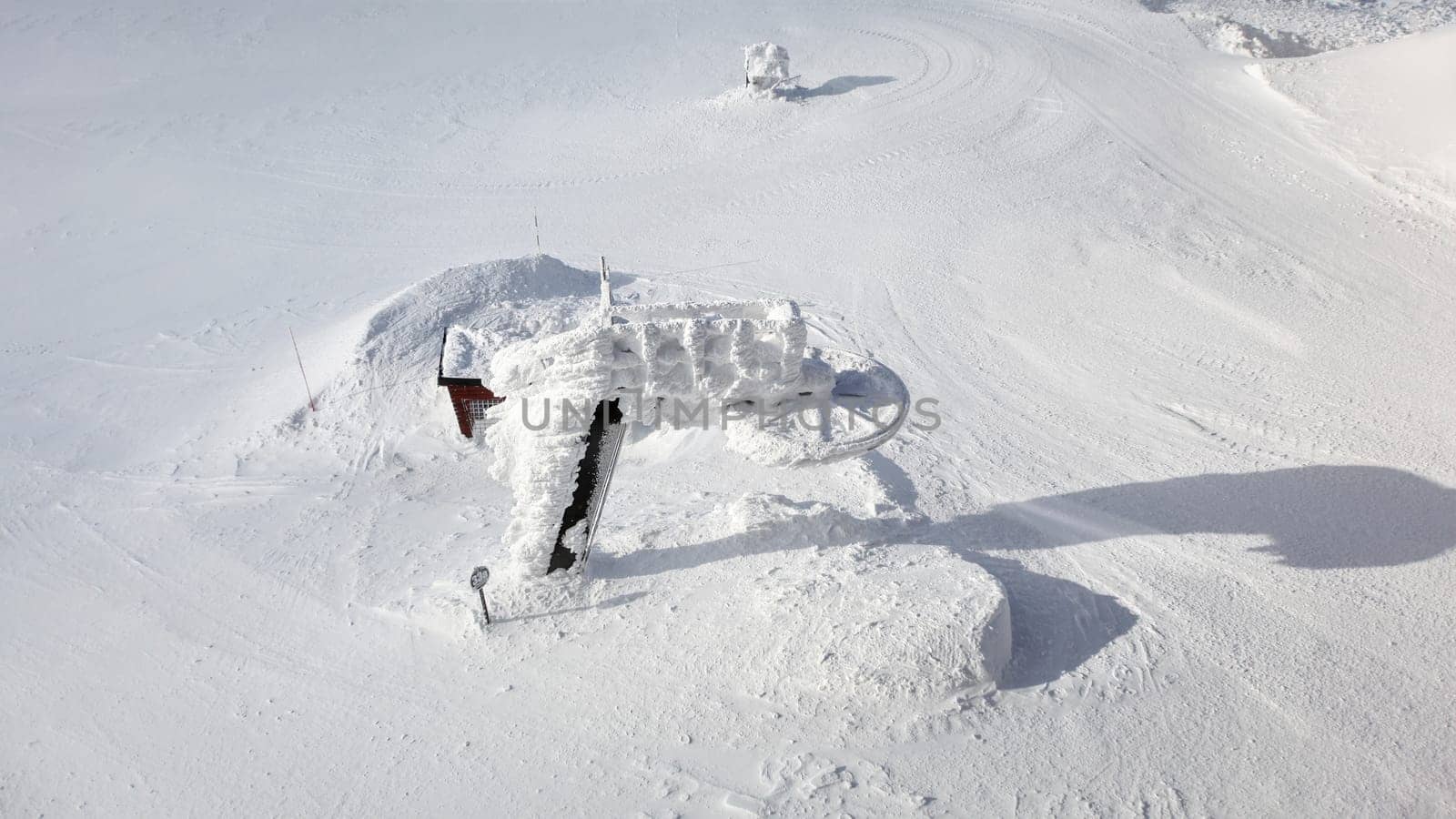 Jasna, Slovakia - January 18, 2018: Old unused ski lift almost completely covered in snow loadings, with white landscape around on sunny winter day. Example of Slovak skiing pistes.