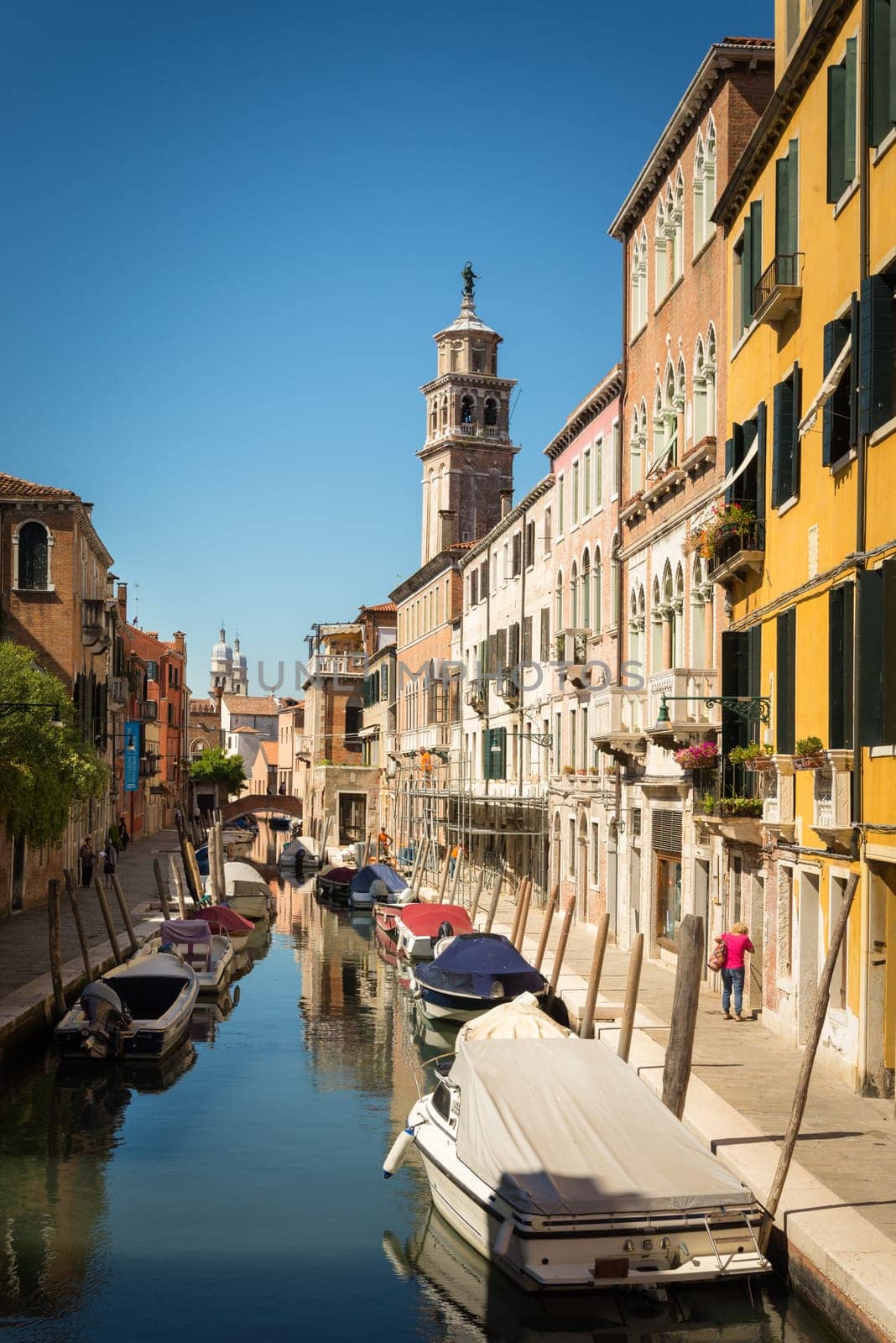 Venice, italy: amll canal with boats and church