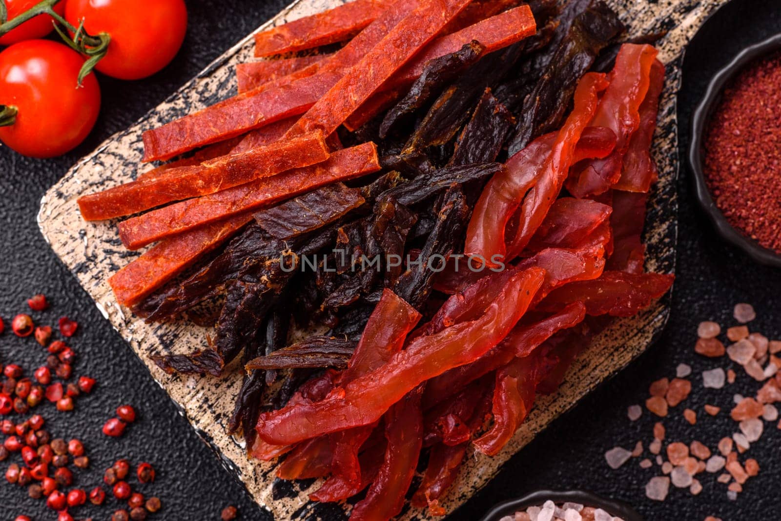 Jerky, dried fish in the form of sticks with salt, spices and herbs on a dark concrete background