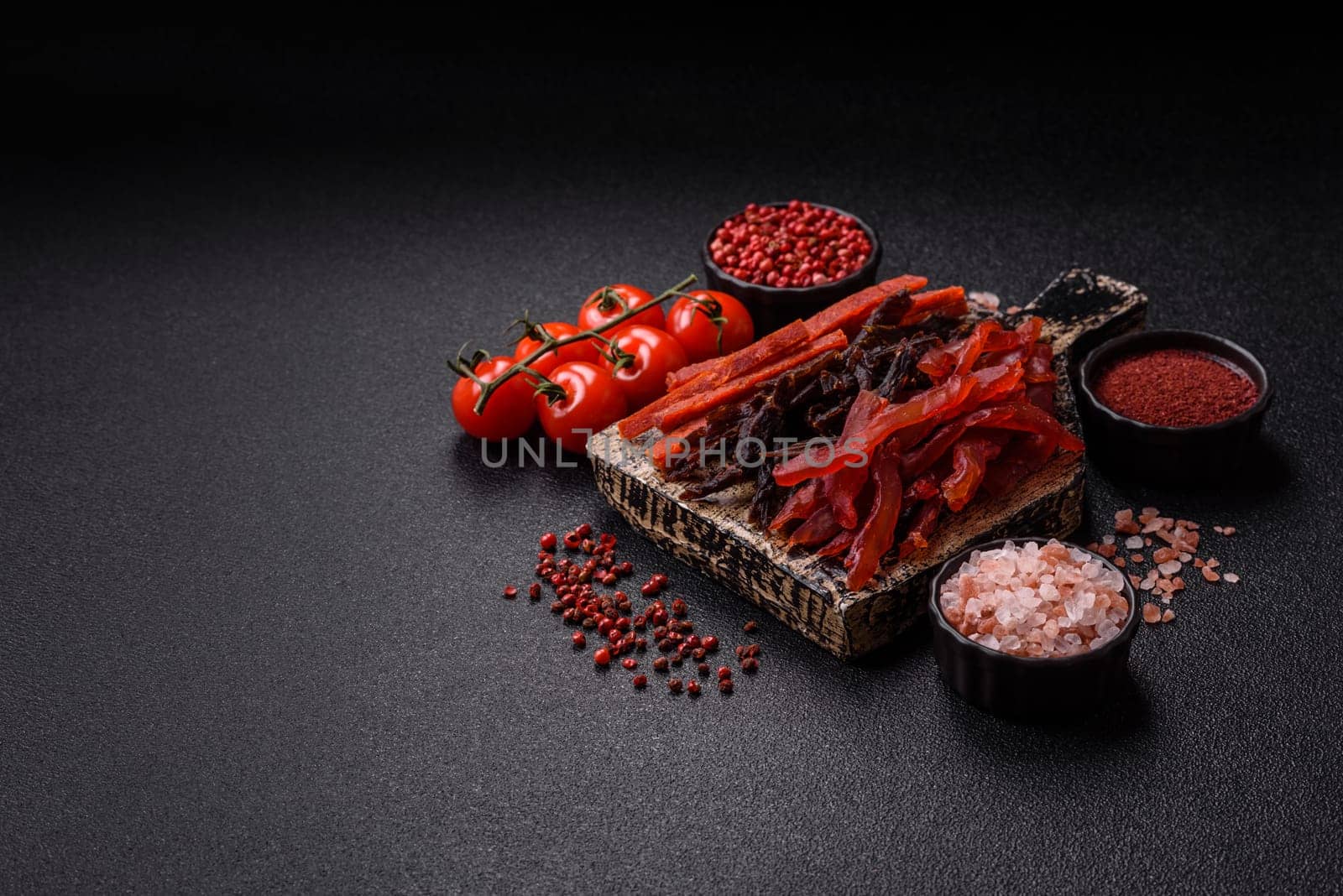Jerky, dried fish in the form of sticks with salt, spices and herbs on a dark concrete background