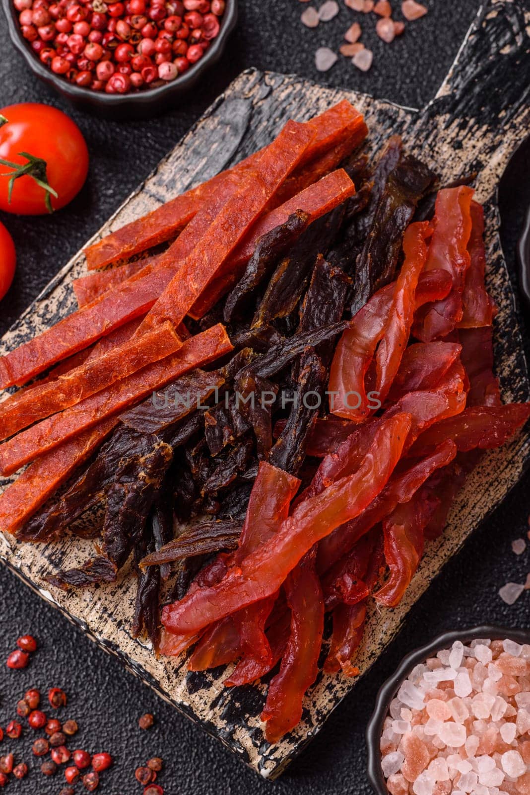 Jerky, dried fish in the form of sticks with salt, spices and herbs on a dark concrete background