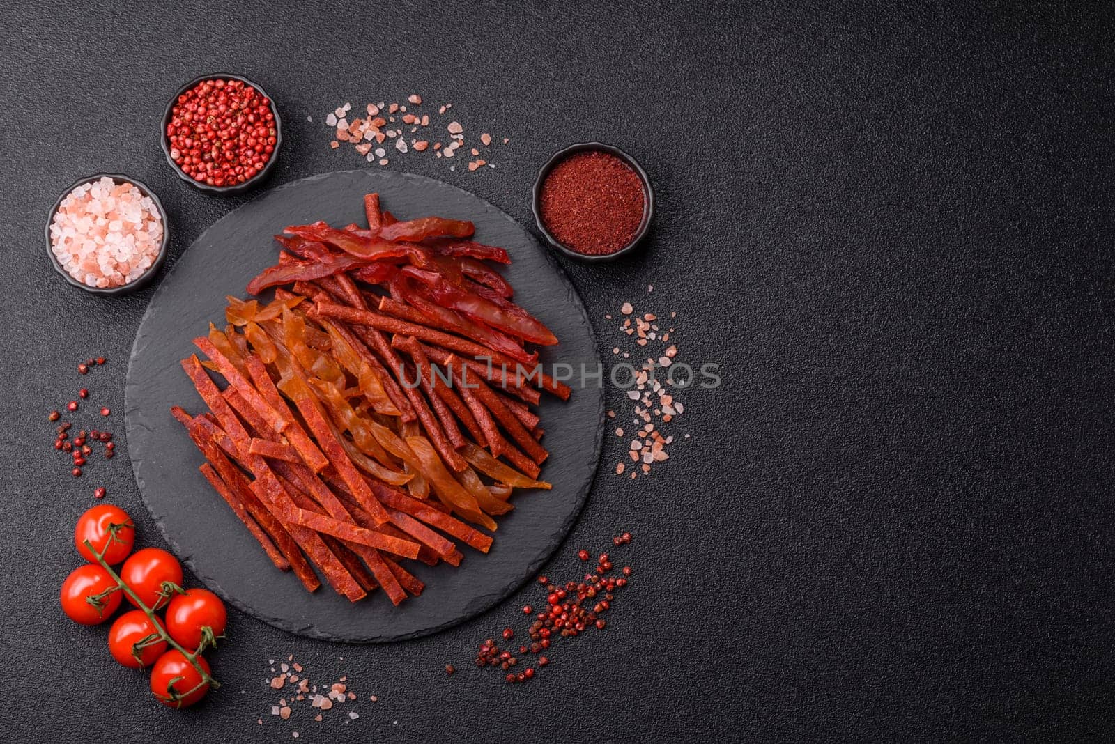 Jerky, dried fish in the form of sticks with salt, spices and herbs on a dark concrete background