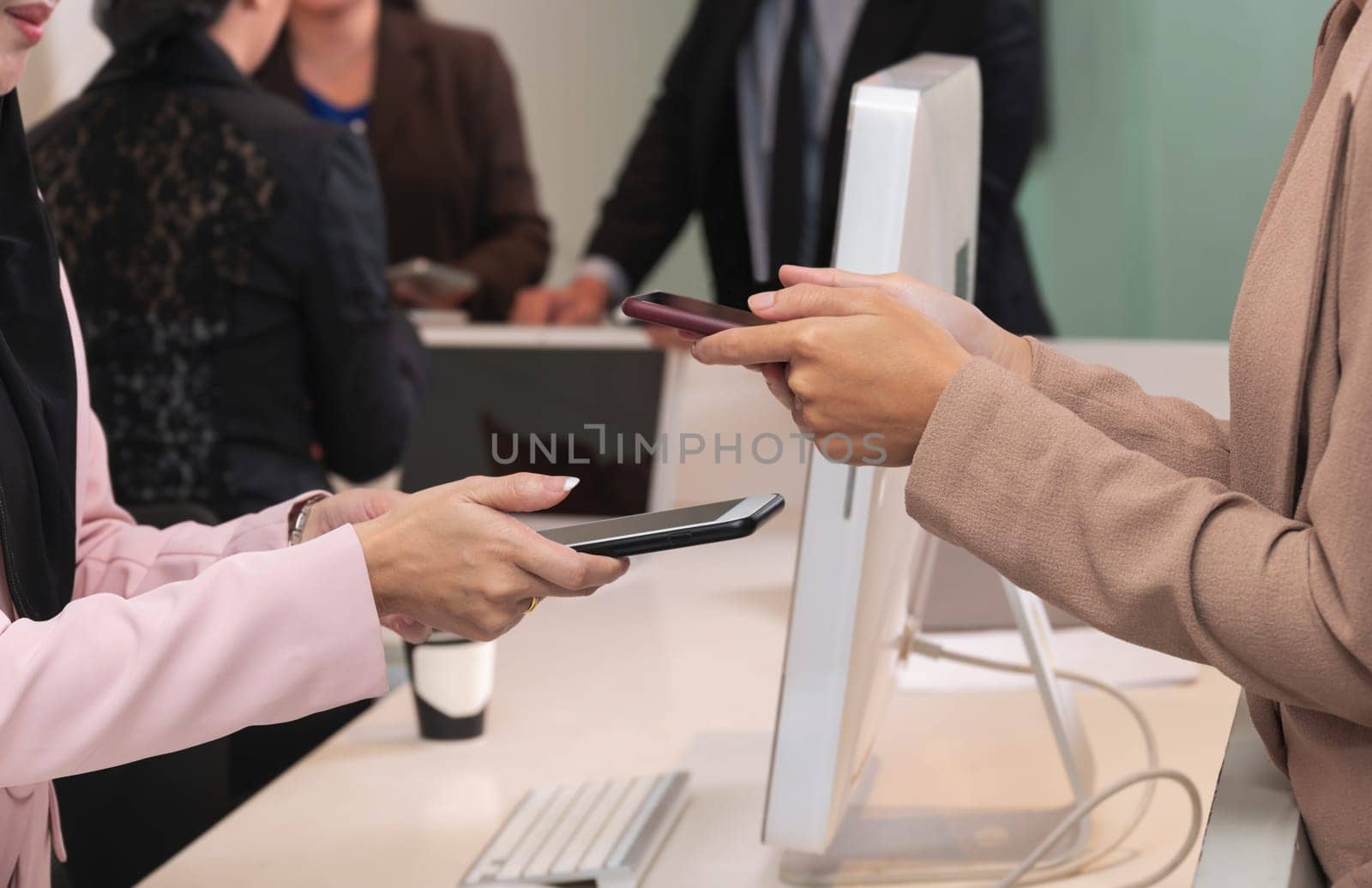 Closeup women hands holding mobile phone for wireless digital payment transactions at counter service. Customer contactless technology payment concept