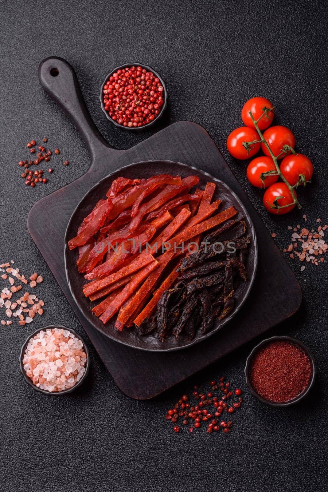 Jerky, dried fish in the form of sticks with salt, spices and herbs on a dark concrete background