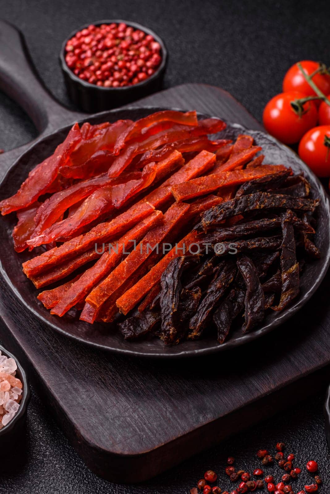 Jerky, dried fish in the form of sticks with salt, spices and herbs on a dark concrete background