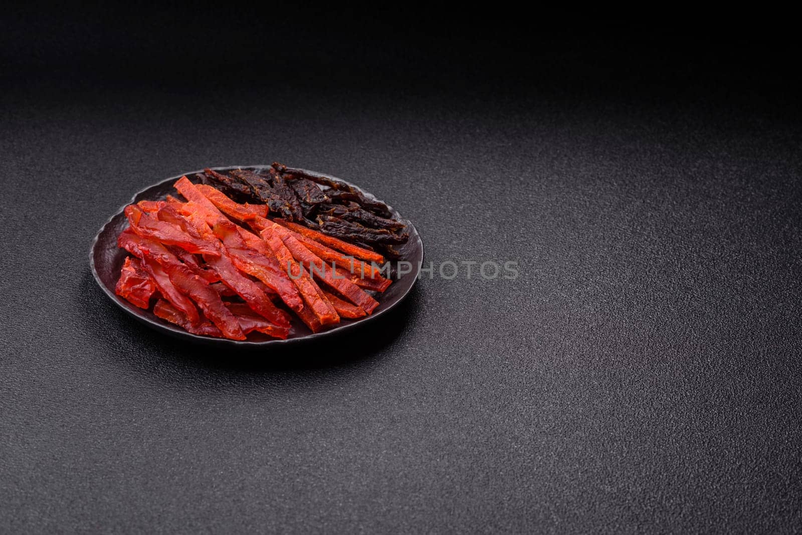 Jerky, dried fish in the form of sticks with salt, spices and herbs on a dark concrete background