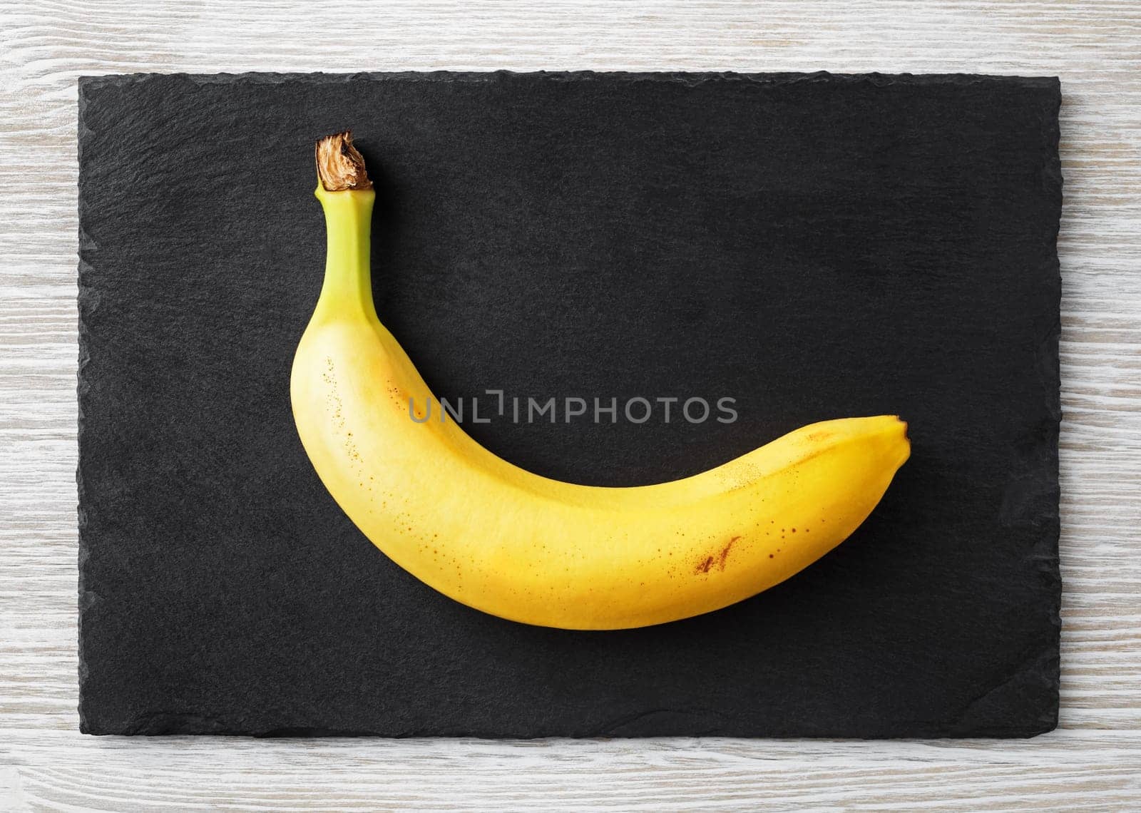Delicious ripe banana on stone board. Flat lay.