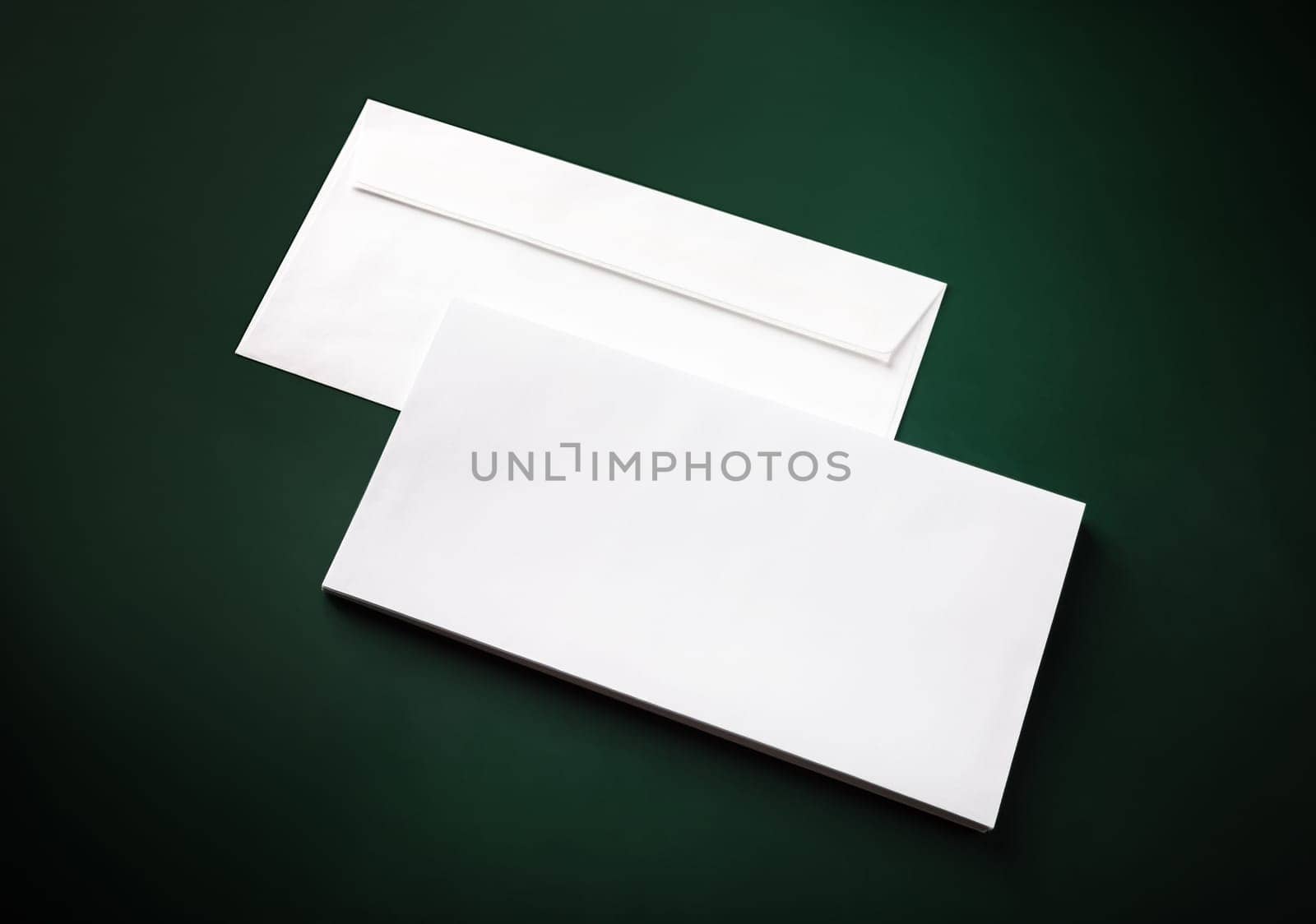 Two blank white envelopes on green background. Copy space.