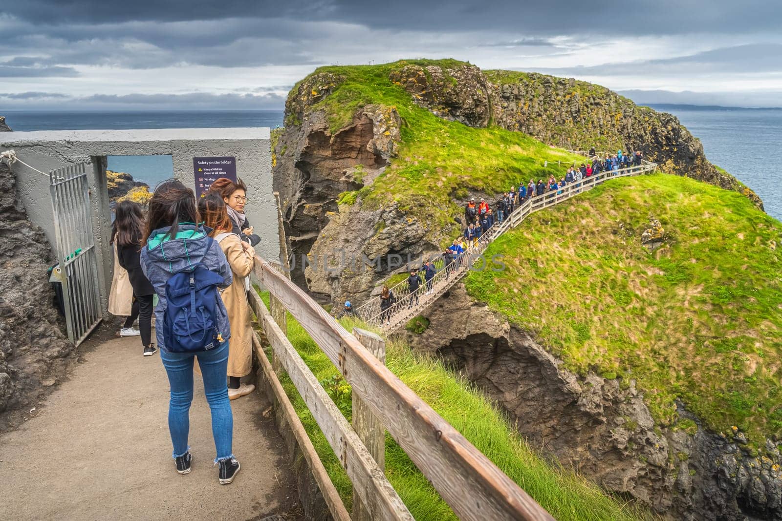 Ballycastle, August 2019 Group of people queueing to crossing Carrick a Rede rope bridge, Wild Atlantic Way, Northern Ireland