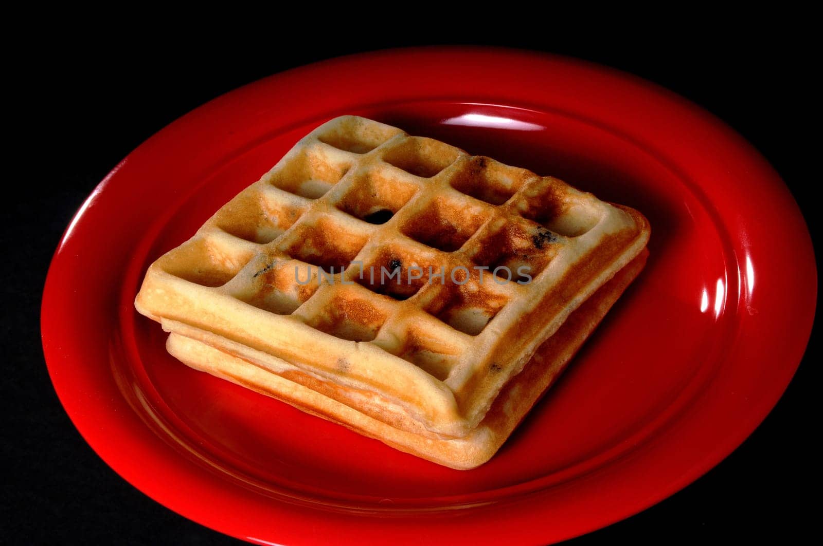 Two Blueberry Waffles On Red Plate isolated over black